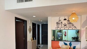 A modern kitchen with a refrigerator, a sink, and a countertop. There is a dining area with a table and chairs. - Modern Comforts: Al Raha Beach modern 1 bedroom near AD airport (Abu Dhabi)