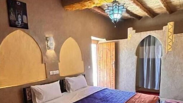 Una habitación con cama, techo de madera y alfombra estampada.