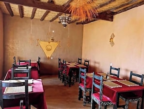 A dining area with tables and chairs, a hanging light fixture, and a wall-mounted light.
