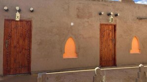 A building with two wooden doors and two arched windows. - Riad Dar Menorca - Peaceful Desert Stay with Patio at the Foot of the Dunes (Merzouga)