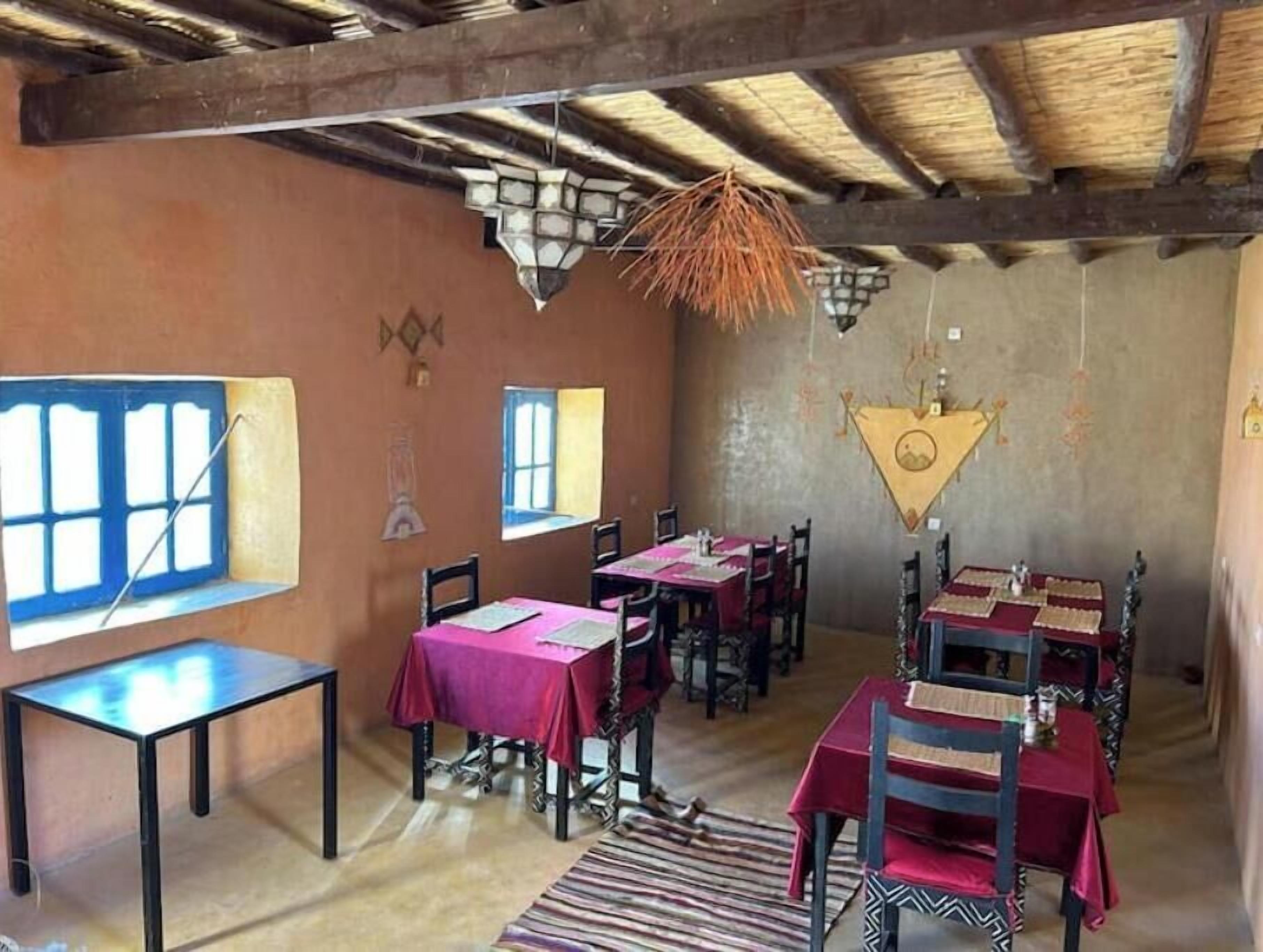 Un espace repas avec des tables et des chaises, un plafond en chaume et une fenêtre donnant sur un paysage agréable.