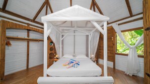Ein Zimmer mit Baldachinbett, Holzwänden und Blick auf Grünflächen.