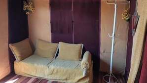 Ein gemütliches Zimmer mit einer Couch, einer hängenden Pflanze und einem Kleiderständer.