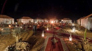 A series of tents with a central walkway, surrounded by small structures and lanterns.
