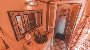 A bathroom with a large mirror, a sink, and a patterned shower curtain.