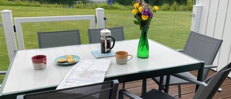 Une table avec une carte, une cafetière, une tasse, des biscuits et un vase rempli de fleurs.