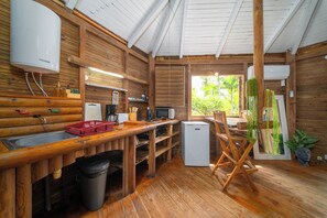 Eine Holzhütte mit Küchenzeile, inklusive Spüle, Kühlschrank und Holztisch.