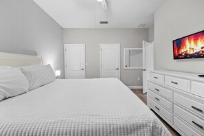 A bedroom with a bed, a dresser, and a television displaying a fireplace. - 4BR house with private pool in Storey Lake (Kissimmee)