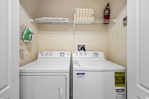 A laundry room with two stacked washers and dryers, a fire extinguisher, and a shelf with towels and an iron. - 4BR house with private pool in Storey Lake (Kissimmee)