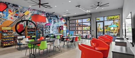 A vibrant indoor space with colorful chairs, tables, and a mural wall.