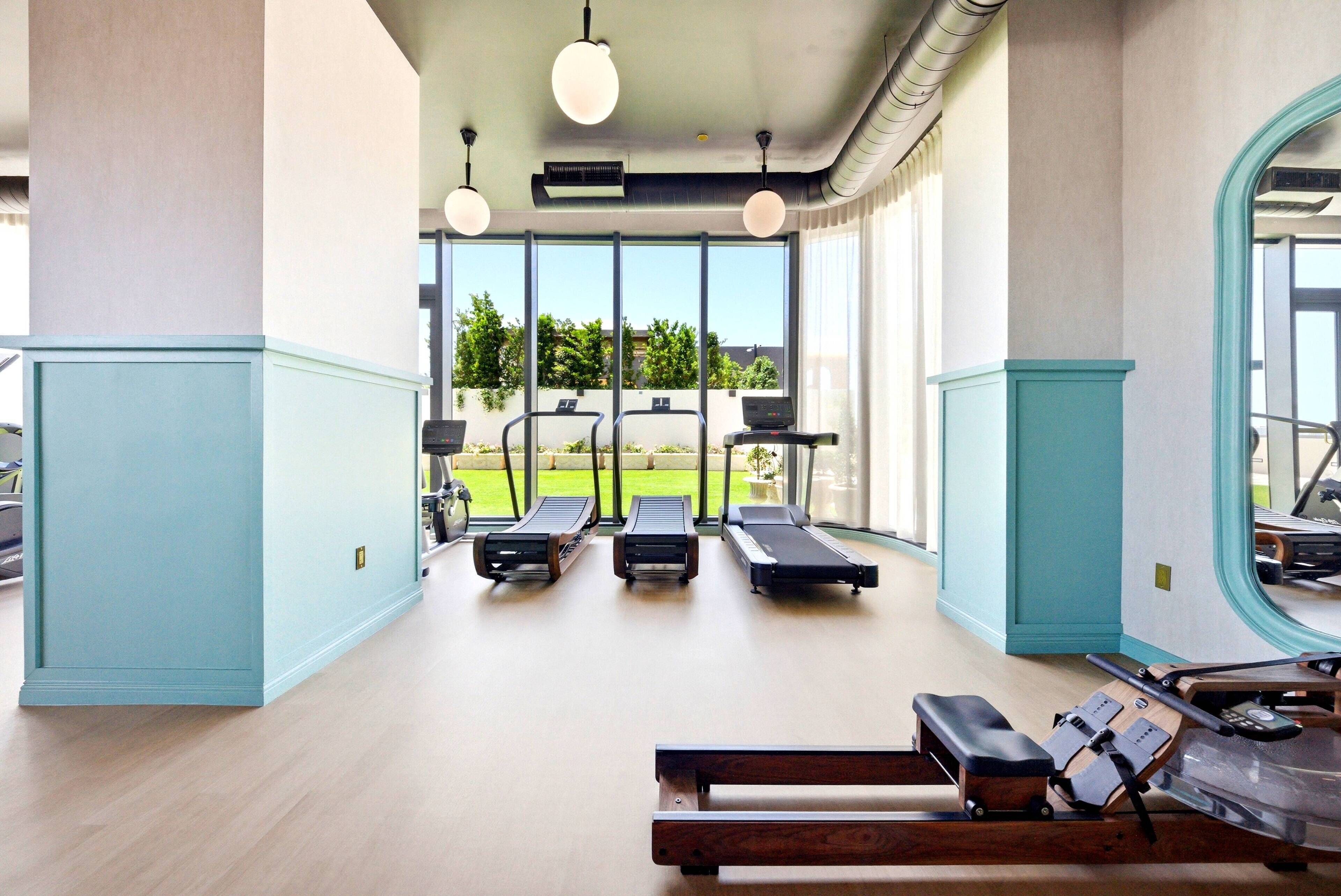 Ein Fitnessraum mit Laufbändern, Rudergerät und einer Hantelbank.
