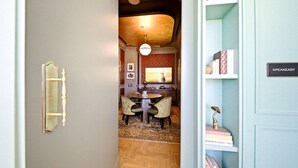 A hallway leading to a dining area with a round table and chairs, a patterned floor, and a bookshelf with books and a trophy. - Apartment at Nomad Residences Wynwood with 2BR (Miami)