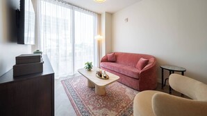 A living room with a sofa, a coffee table, a TV mounted on the wall, and a lamp. - Apartment at Nomad Residences Wynwood with 2BR (Miami)
