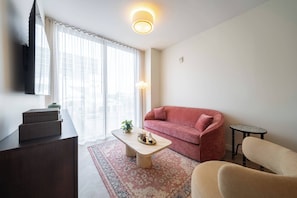 Ein Wohnzimmer mit Sofa, Couchtisch, Wandfernseher und Lampe.