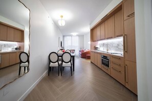 Eine moderne Küche mit Holzschränken, einem Essbereich mit Stühlen und einem großen Spiegel an der Wand.