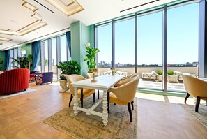A spacious room with a large dining table, comfortable seating, and a view of the cityscape through large windows. - 2BR apartment with heated pool in miami (Miami)