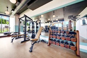 Een sportschool met trainingsapparatuur, een bank en een dumbbellsrek.