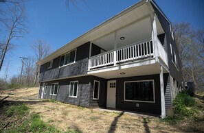 Een twee verdiepingen tellend huis met een balkon, grote ramen en een voordeur.