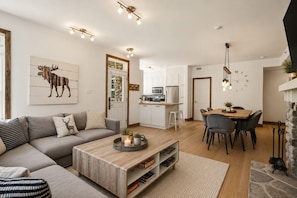 Ein modernes Wohnzimmer mit einer Couch, einem Couchtisch und einem Essbereich mit Stühlen und Tisch.