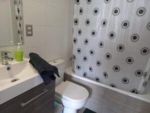 Et badeværelse med toilet, vask og bruseforhæng.