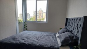 Une chambre à coucher avec un lit, une fenêtre et une vue sur des immeubles.