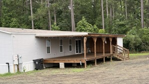 A single-story building with a wooden porch and a small staircase leading to a covered area. -  Cozy Lake Getaway Near Toledo Town (Many)