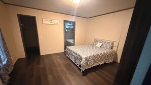 A bedroom with a bed, a door, a wall with a sign, a closet, and a vent. -  Cozy Lake Getaway Near Toledo Town (Many)