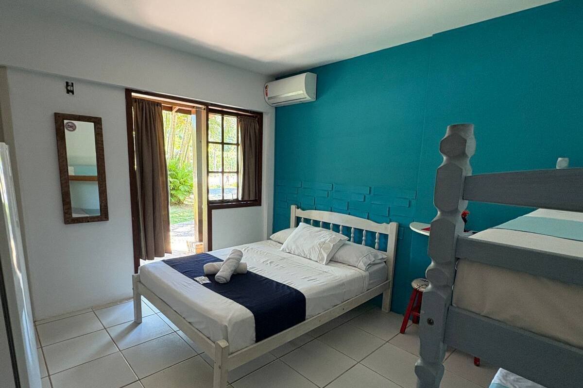 Un dormitorio con una cama individual, una ventana con cortinas, un ventilador de techo y un equipo de aire acondicionado.