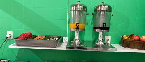 A breakfast buffet with various food items and two beverage dispensers.