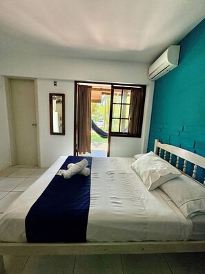 Un dormitorio con una cama, una ventana con cortinas, un equipo de aire acondicionado y una puerta.