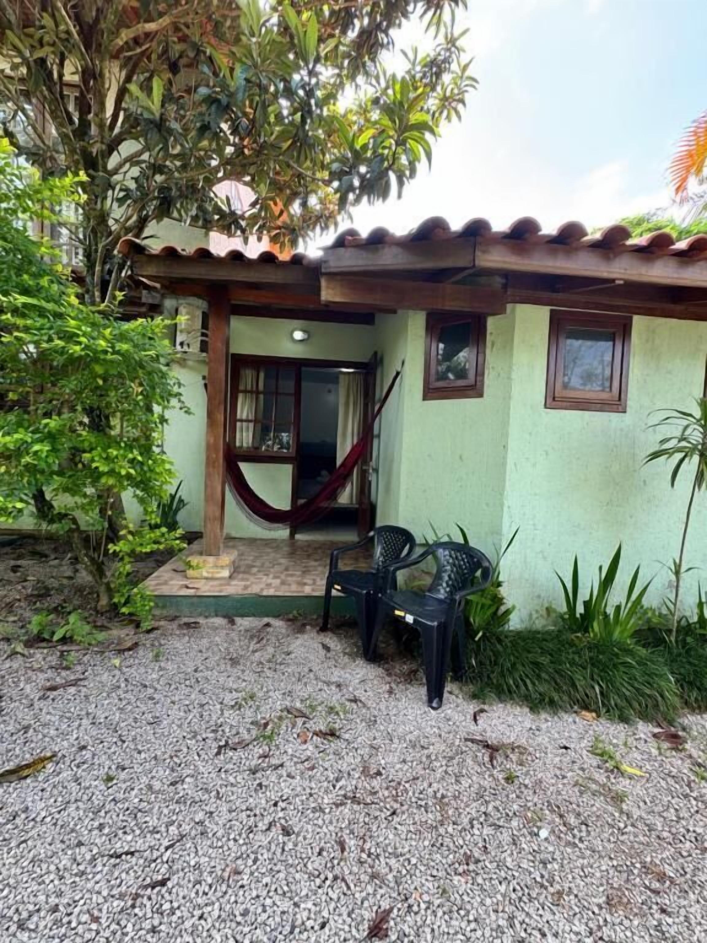 A house with a tiled roof, a hammock, and a small patio area with chairs.