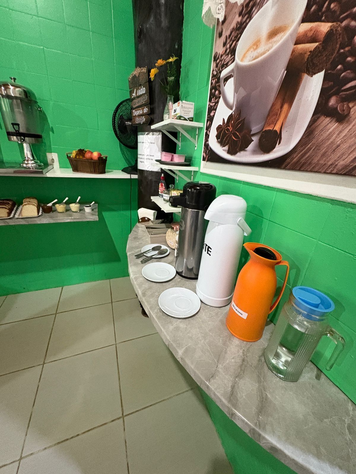 Una encimera de cocina con una cafetera, un termo, una jarra y una botella de agua.