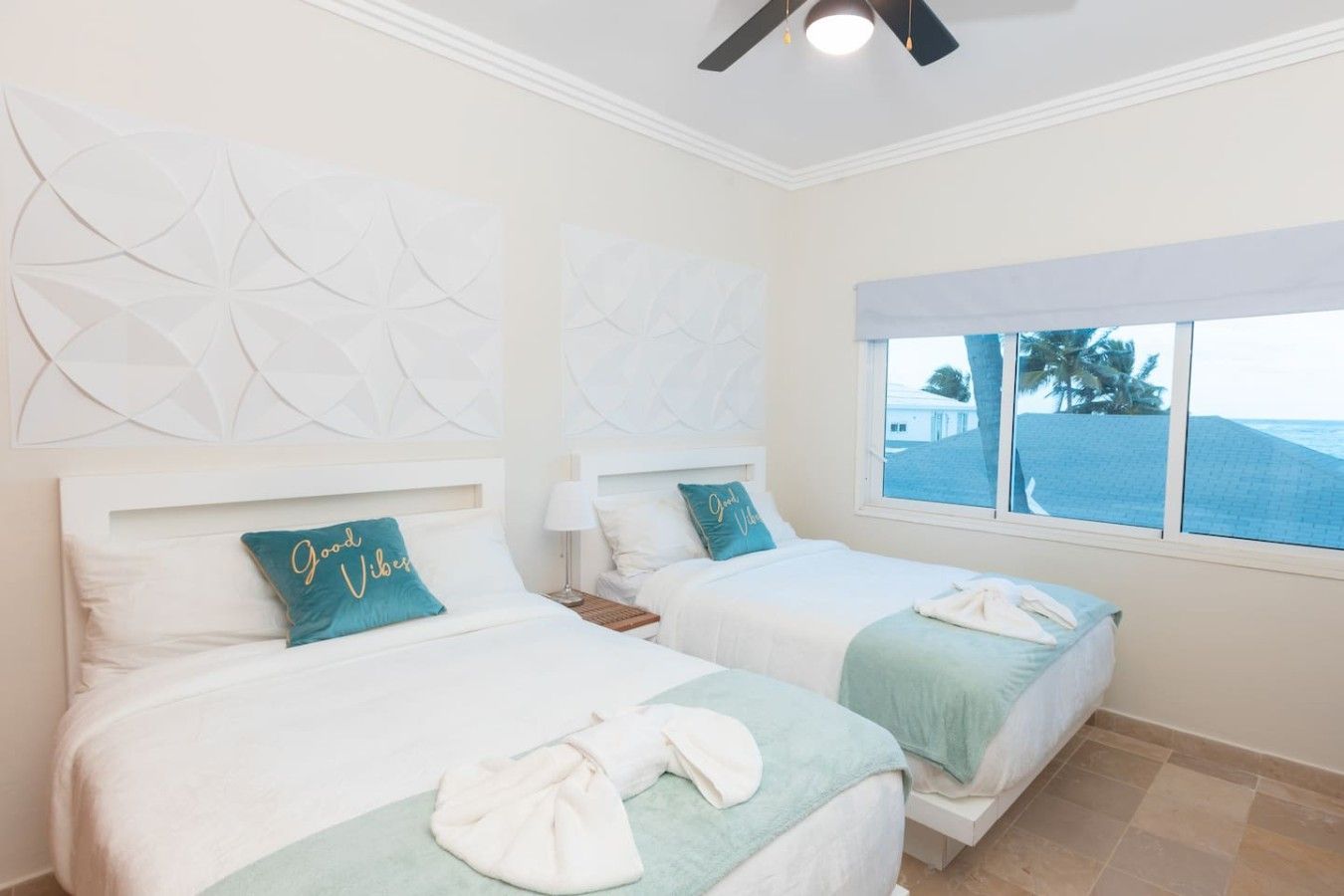 A hotel room with two beds, a window with a view of the beach, and decorative wall art.