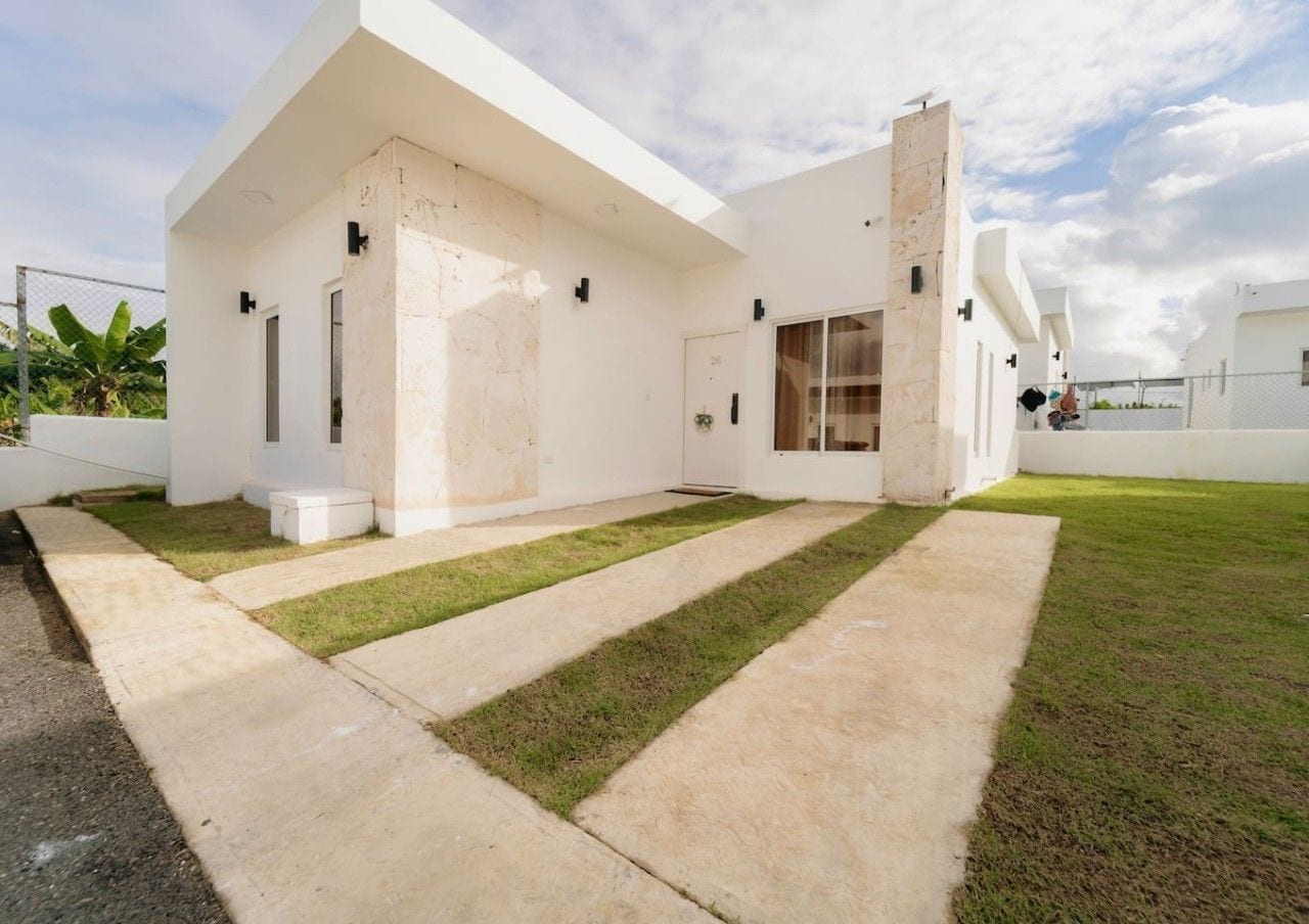 A modern house with a flat roof, large windows, and a well-maintained lawn.