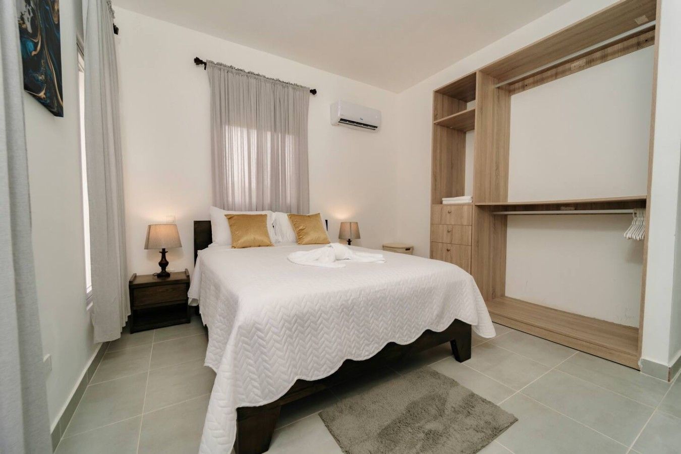 A bedroom with a bed, bedside lamps, a wardrobe, and a window with curtains.