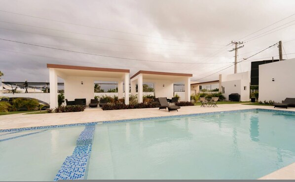 A modern outdoor pool area with lounge chairs and a covered patio. - Family Villa w/ Pool & BBQ, 5 Min from Macao Beach (Punta Cana)