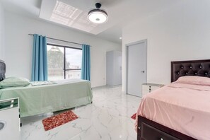 Une chambre à coucher avec un lit, un bureau, une armoire et une fenêtre avec des rideaux.