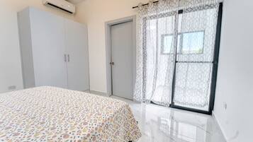 Une chambre à coucher avec un lit, une armoire et une fenêtre ornée de rideaux à motifs.