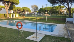 Ein Schwimmbecken mit Rettungsboje, umgeben von Gras und Bäumen.