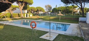 Ein Schwimmbecken mit Rettungsboje, umgeben von Gras und Bäumen.
