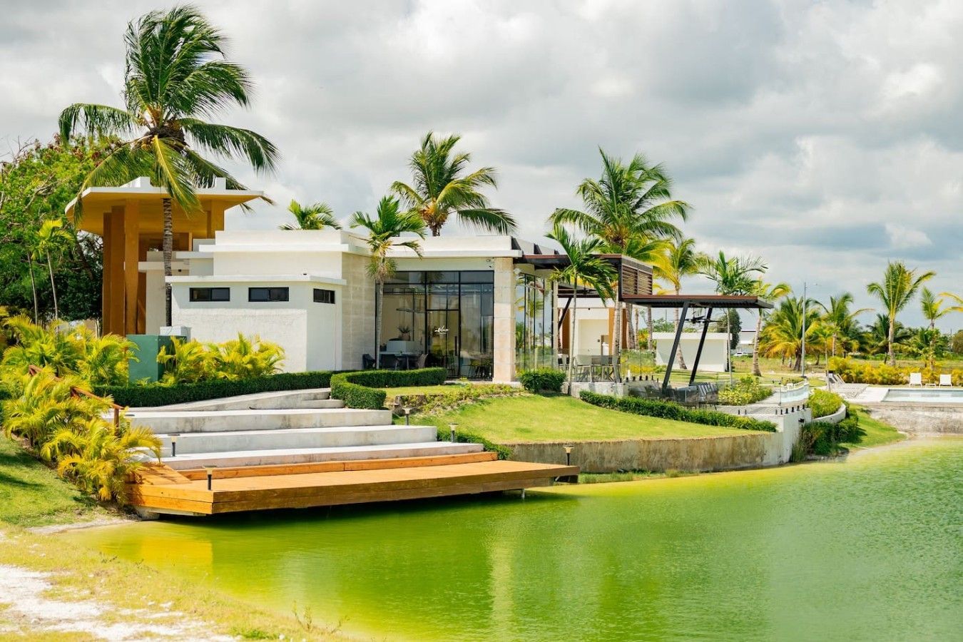 Ein modernes Resort mit Pool, Palmen und einem überdachten Essbereich im Freien.