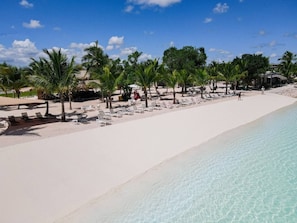 A beach with white sand, clear turquoise water, and palm trees. - 2-Level Retreat + Jacuzzi | FREE Electricity (Punta Cana)