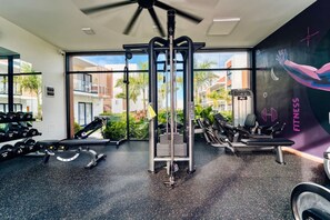 A gym with exercise equipment, large windows, and a view of buildings. - 2-Level Retreat + Jacuzzi | FREE Electricity (Punta Cana)