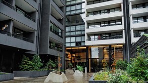 Un edificio de varios pisos con balcones, un área central abierta con macetas y una escalera a la derecha.
