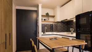 Une cuisine moderne avec une porte sombre, une table en bois et des chaises.