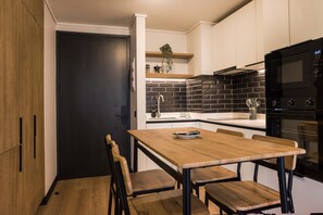 Eine moderne Küche mit einer dunklen Tür, einem Holztisch und Stühlen.
