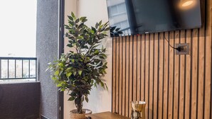 Un salon moderne avec un téléviseur à écran plat fixé à un mur en bois, une plante en pot, une table ronde et un banc.