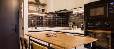 A modern kitchen with a black tiled backsplash, a wooden dining table, and a built-in oven.