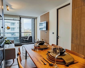 Ein stilvoller Essbereich mit Holztisch, Stühlen und Blick auf die Stadt durch große Fenster.