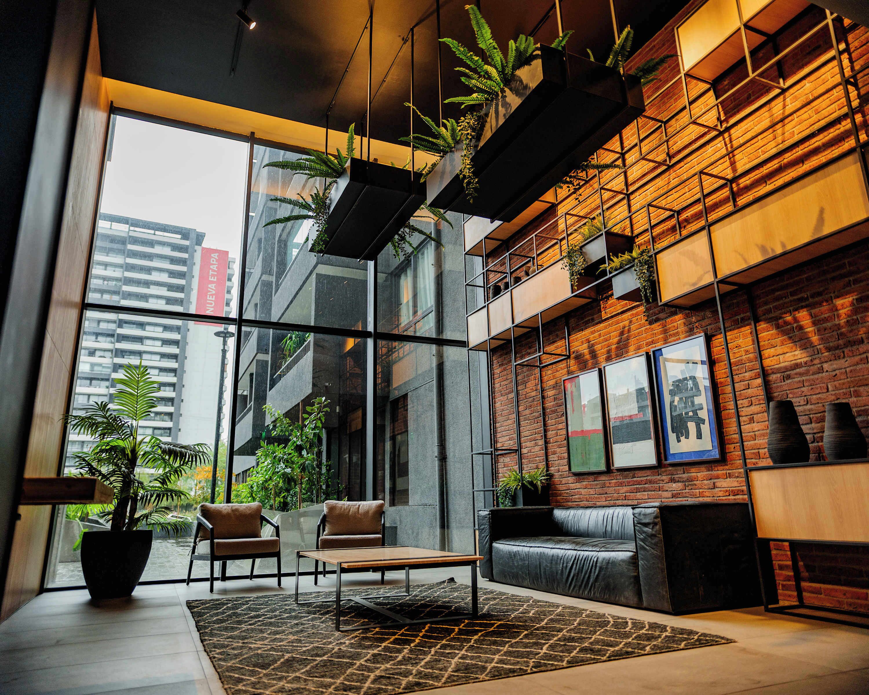 A modern interior with a glass wall, leather seating, and hanging plants.